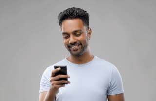 Indian man looking at mobile phone and smiling