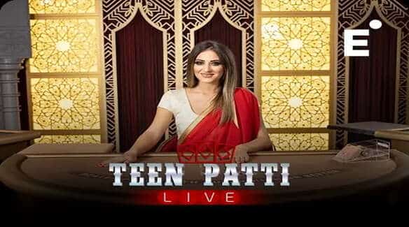 A woman in a white and red saree hosting a game of Teen Patti Live, seated at a card table with ornate golden background panels and the text 'TEEN PATTI LIVE' displayed at the front.